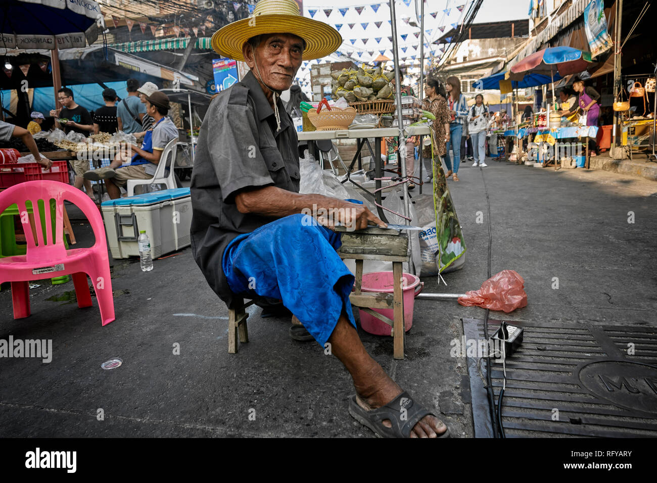 Knife grinder. Elderly Thai man at work in the street. Thailand S. E. Asia Stock Photo