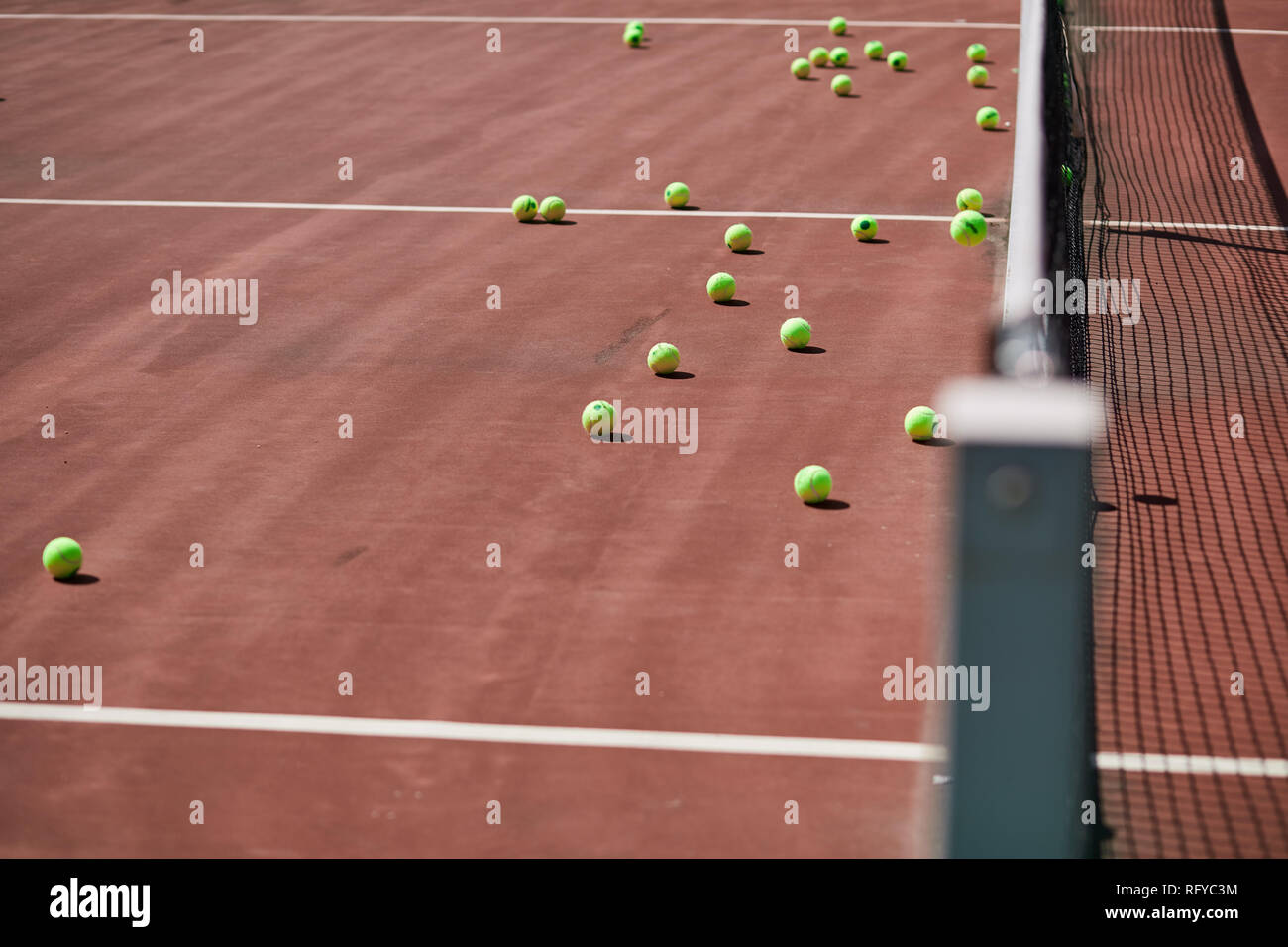 Red-clay tennis court with sport equipment and tennis balls on it. Stock Photo
