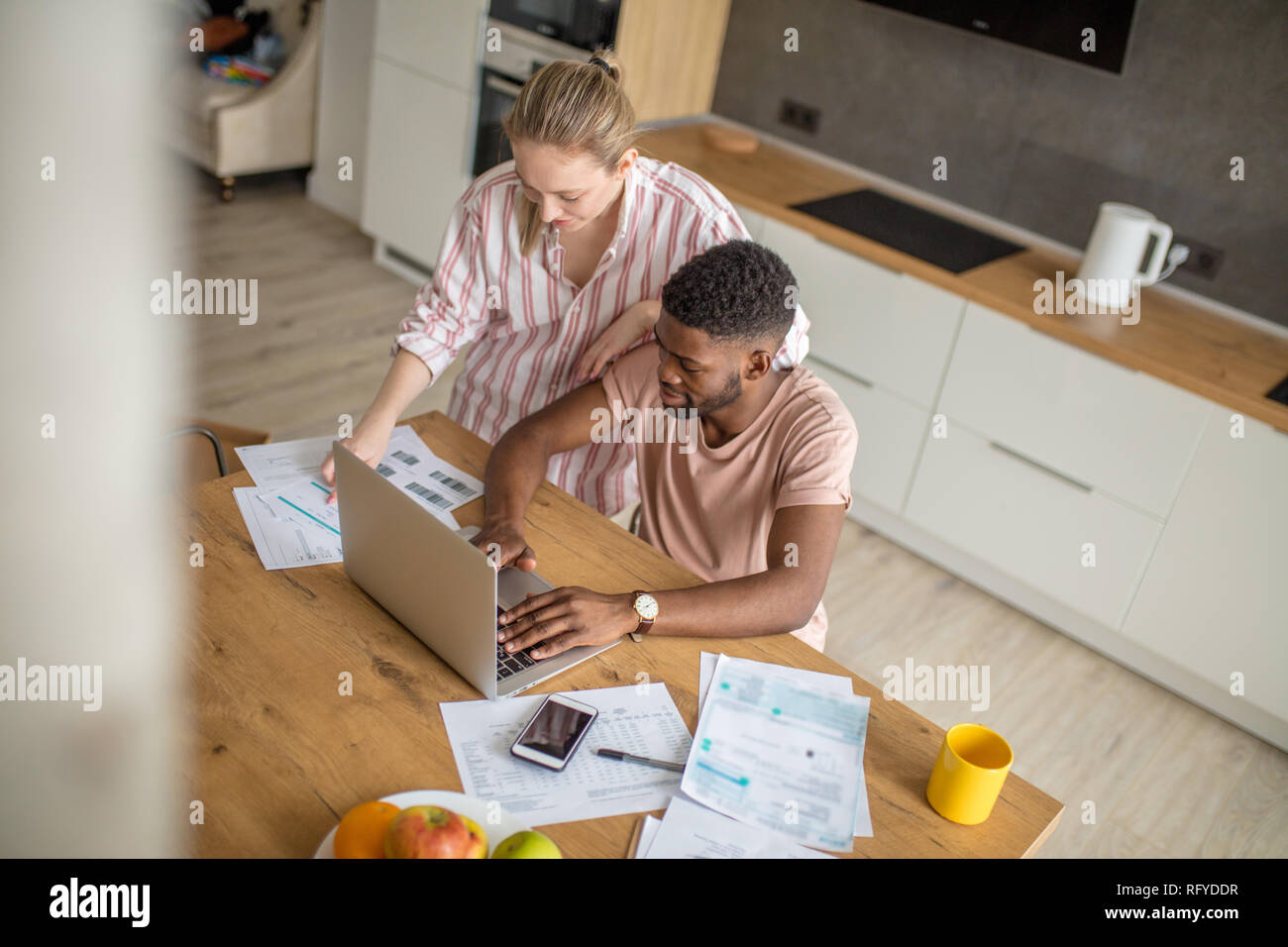 Young interracial couple using laptop together having breakfast at home Stock Photo