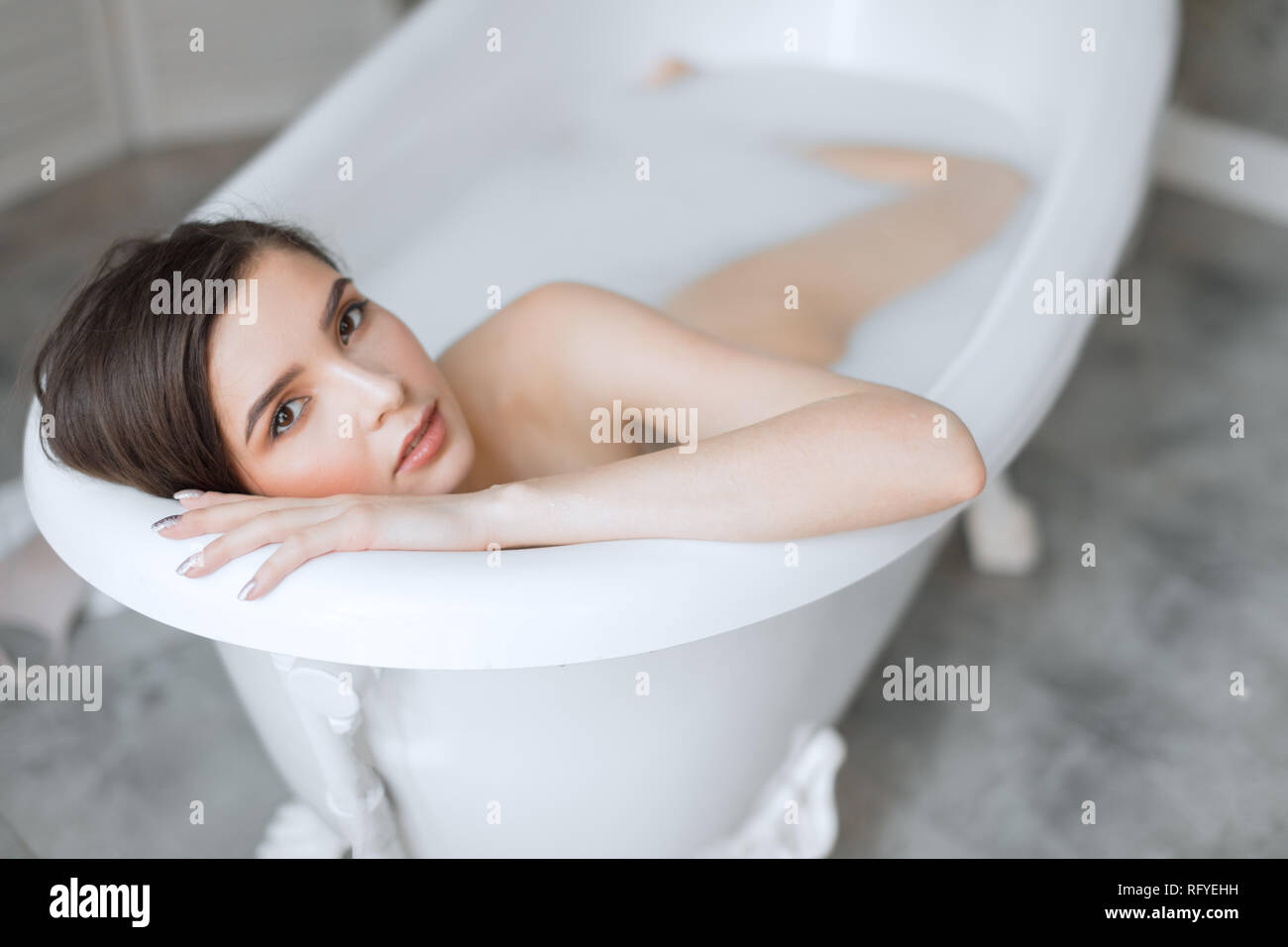 Woman relaxing in milk filled bath in spa centre Stock Photo