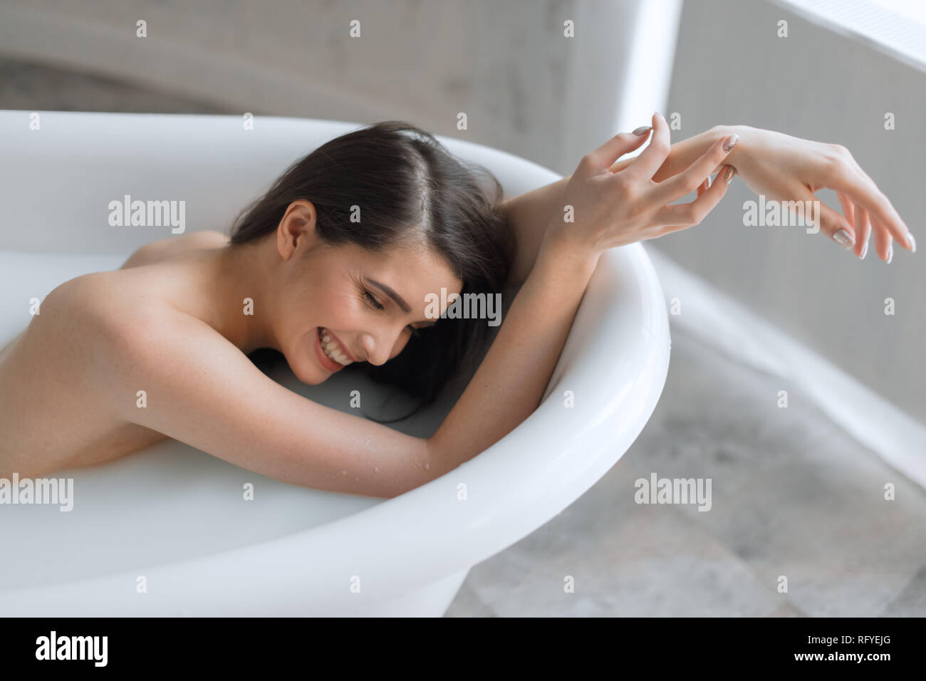 Woman relaxing in milk filled bath in spa centre Stock Photo