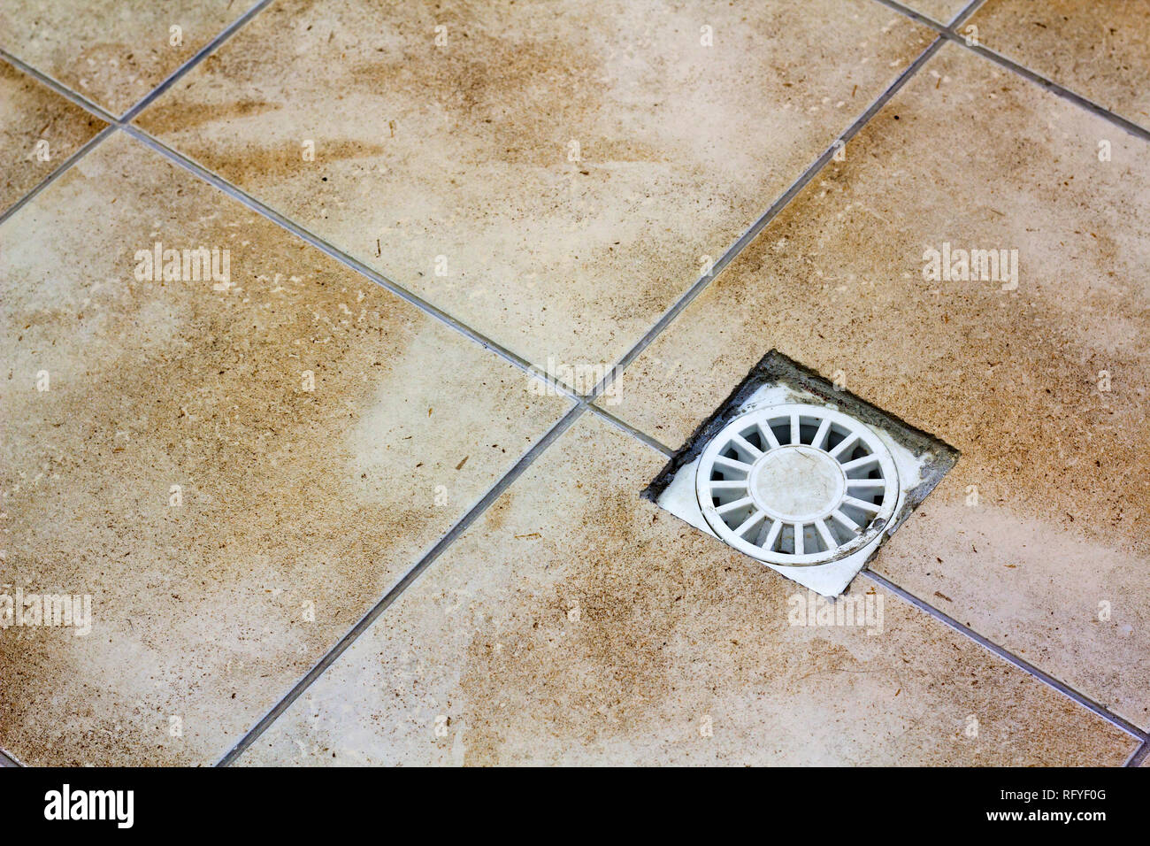 Water drain vent in kitchen, bathroom or basement ceramic tiled old vintage floor. Geometric abstract beige background. Stock Photo