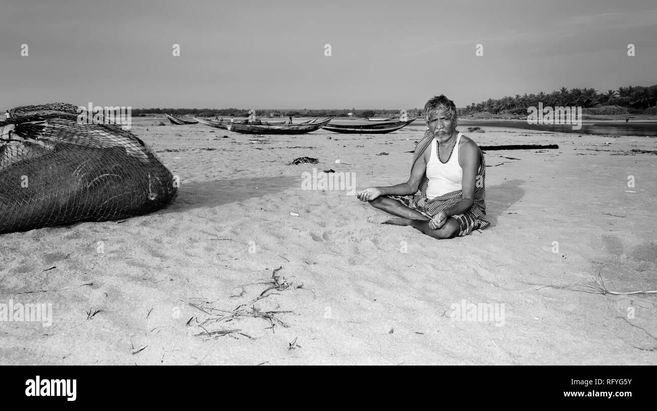 An elderly fisherman sitting on the beach, copy space Stock Photo