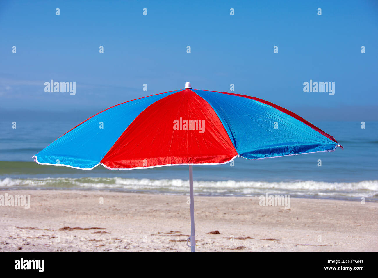 bright red and blue beach umbrella on Florida seashore with ocean background Stock Photo