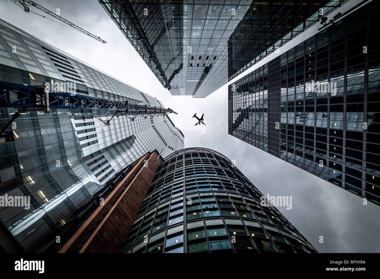 Silhouette of a jet plane flying low over Three different kind of architecture with commercial office buildings exterior in London Stock Photo