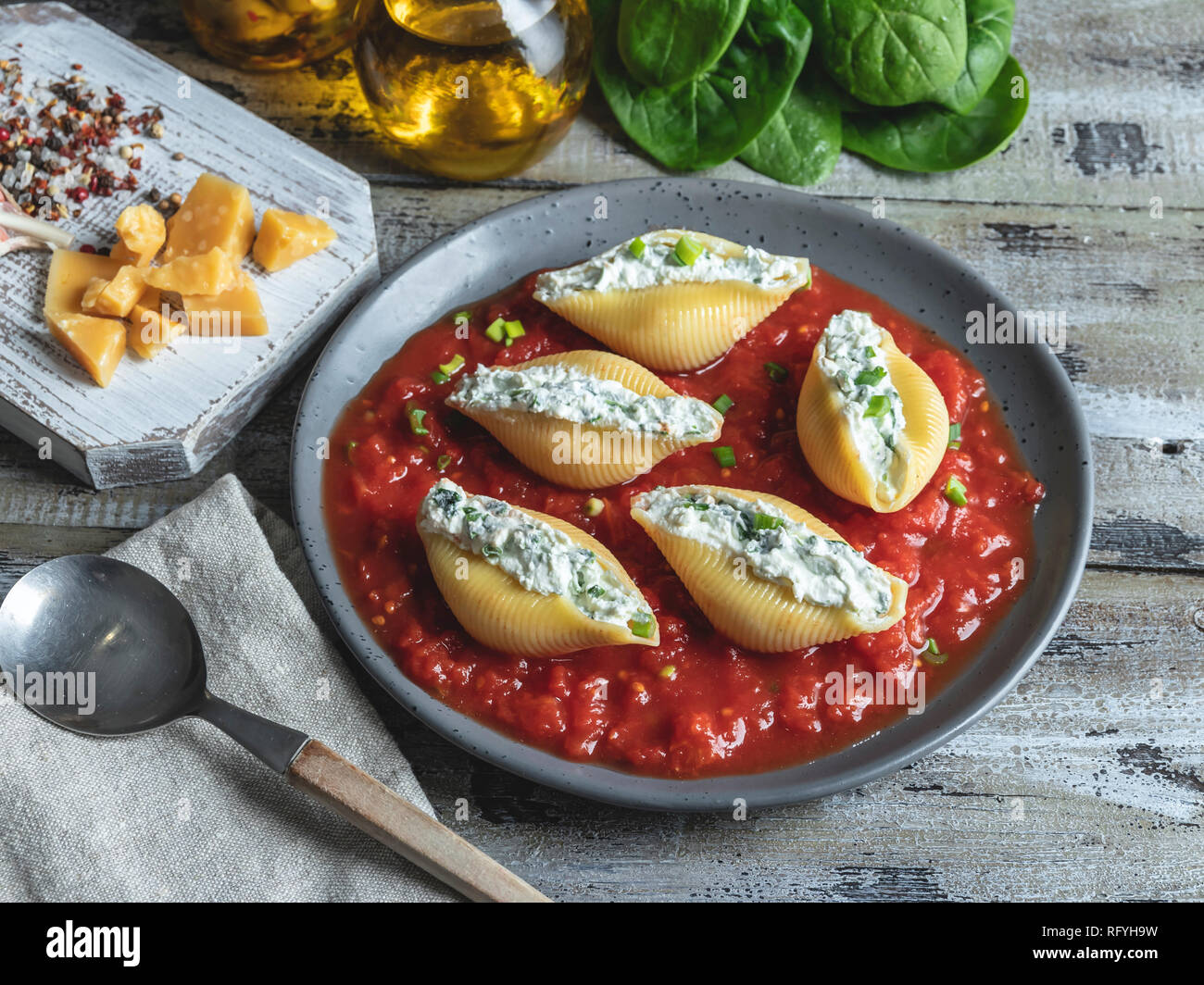 cooked pasta conchiglioni stuffed spinach and cheese, tomato sauce on plate Stock Photo