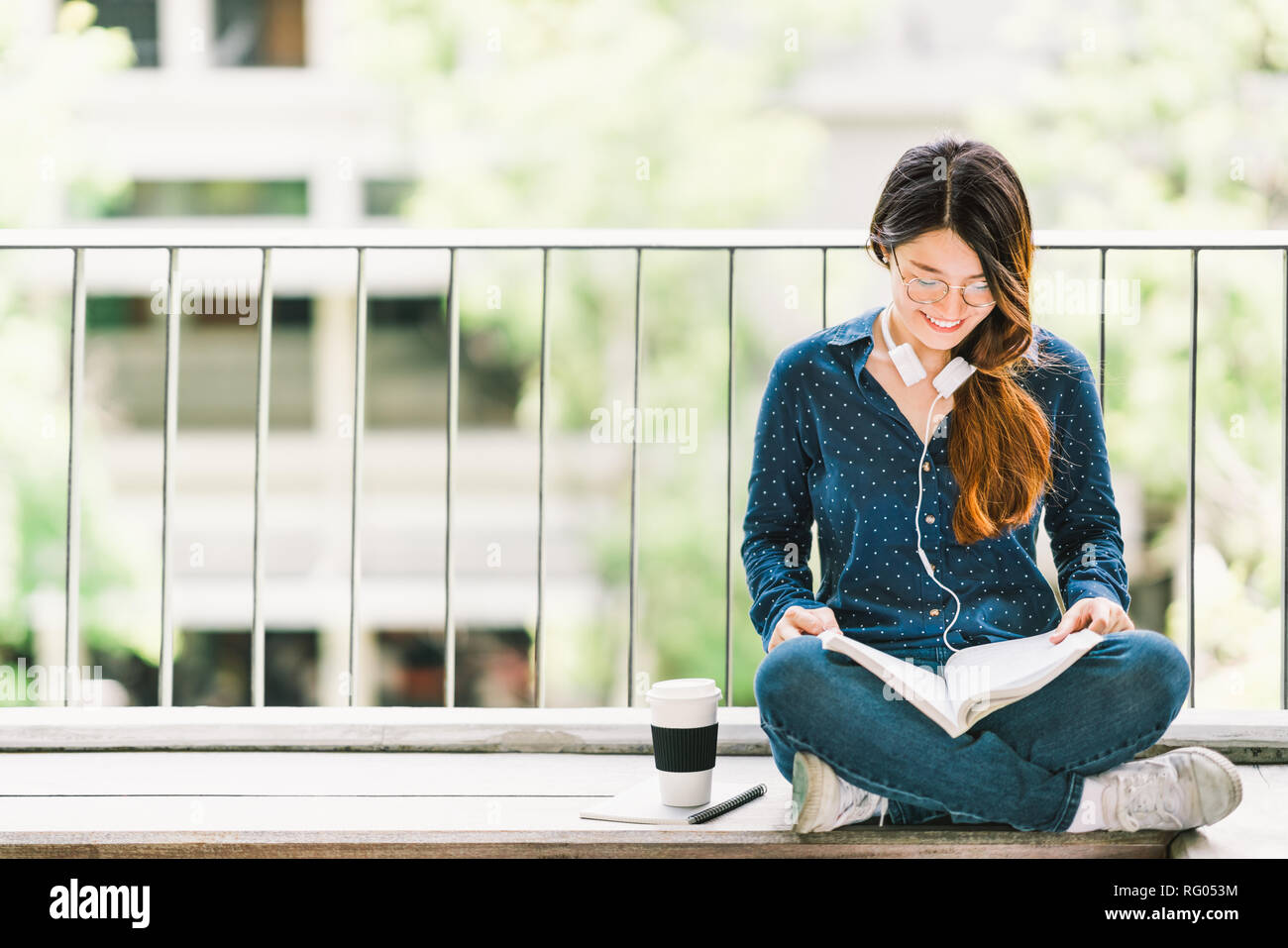 Young Asian college student girl reading book for exam, sitting at university campus with copy space. Education or casual studying lifestyle concept Stock Photo