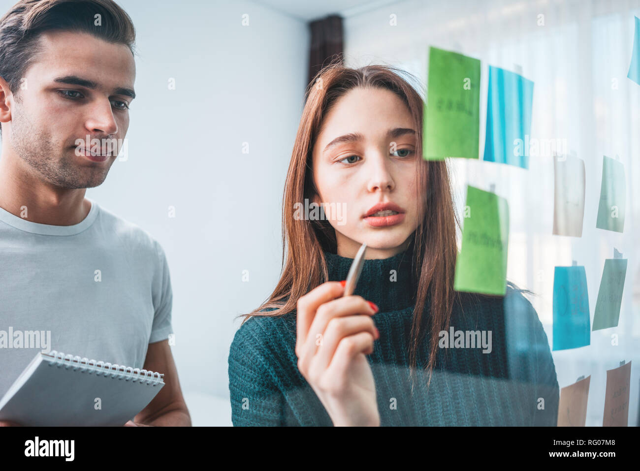 Portrait of coworker people standing at office space behind glass wall with sticky notes. Team of manager disscusing and brainstorming new sturtup ide Stock Photo