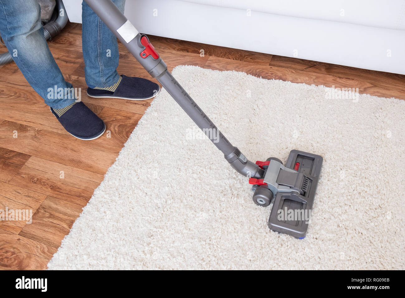 Vacuuming white carpet using the vacuum cleaner Stock Photo Alamy