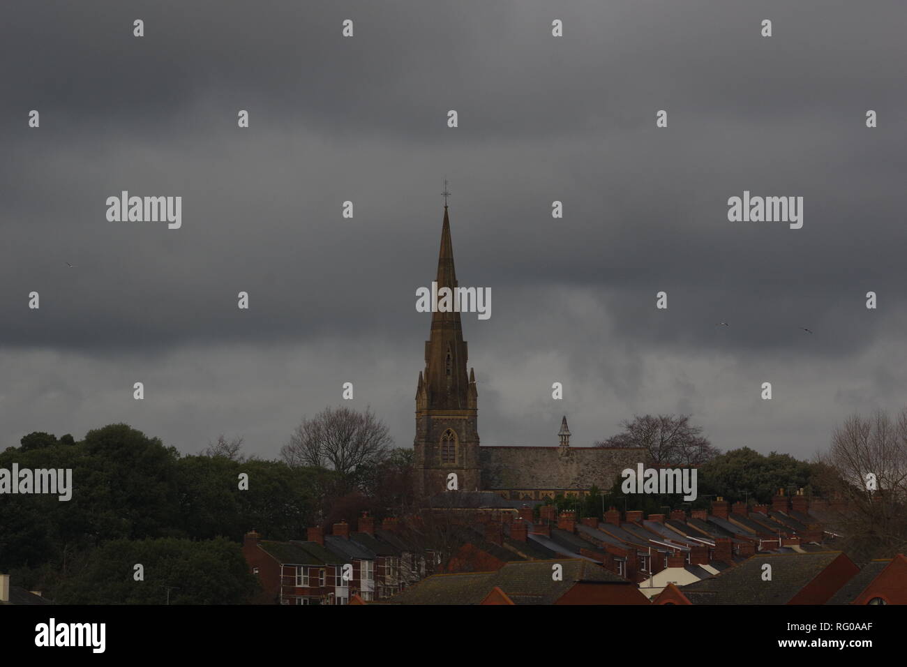 St Leonards Church beyond Trews Weir on the River Exe. on a Gloomy