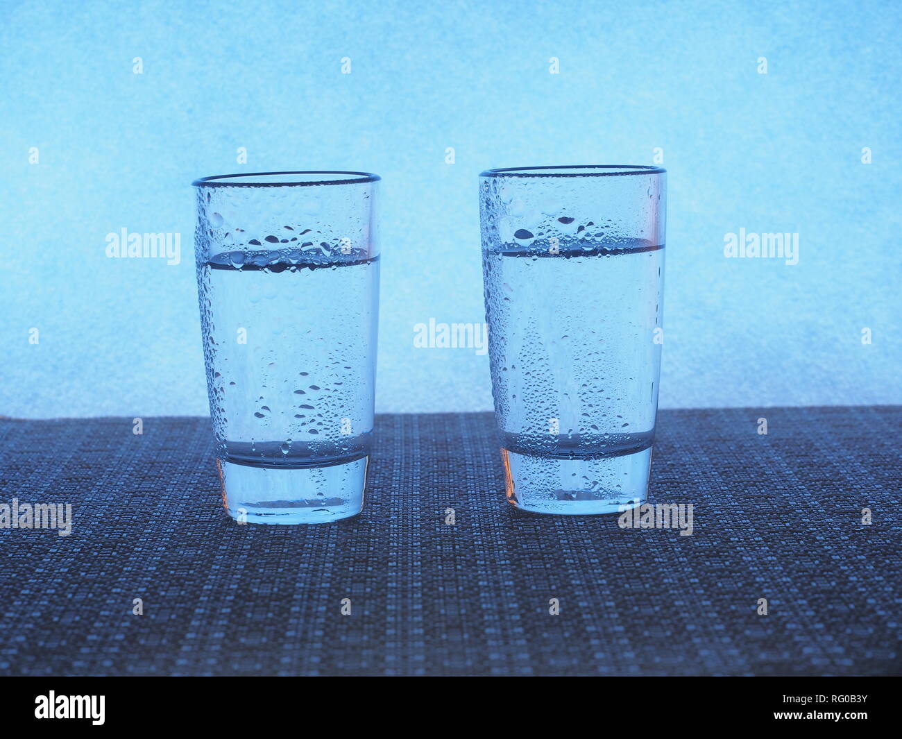 Two glasses of vodka are on the table. The glasses are covered with water droplets. Still-life. Stock Photo