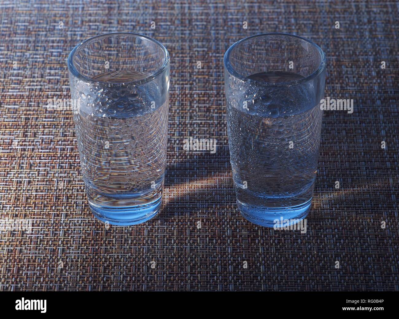 Two glasses of vodka are on the table. The glasses are covered with water droplets. Still-life. Stock Photo