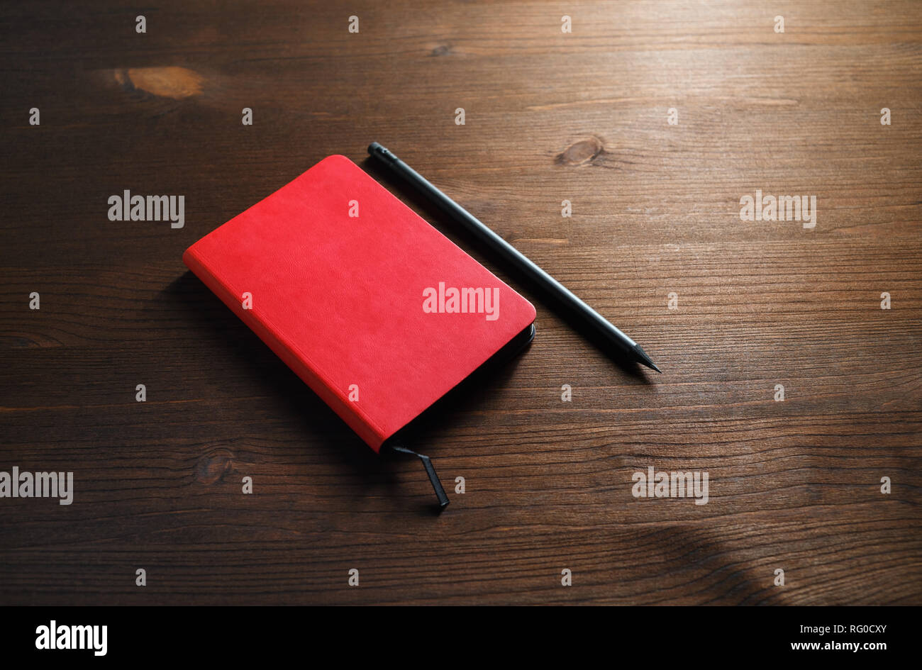 Red notepad and pencil on wood table background. Template for branding ...