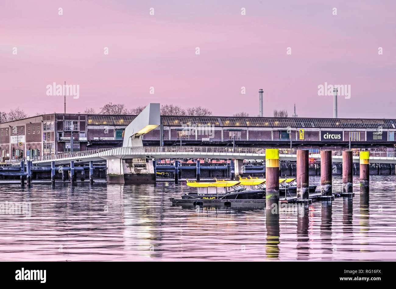 Rotterdam, The Netherlands, January 18, 2019: moored watertaxis, Rijnhaven bridge and Fenix warehouse with food factory and circus school at sunrise Stock Photo