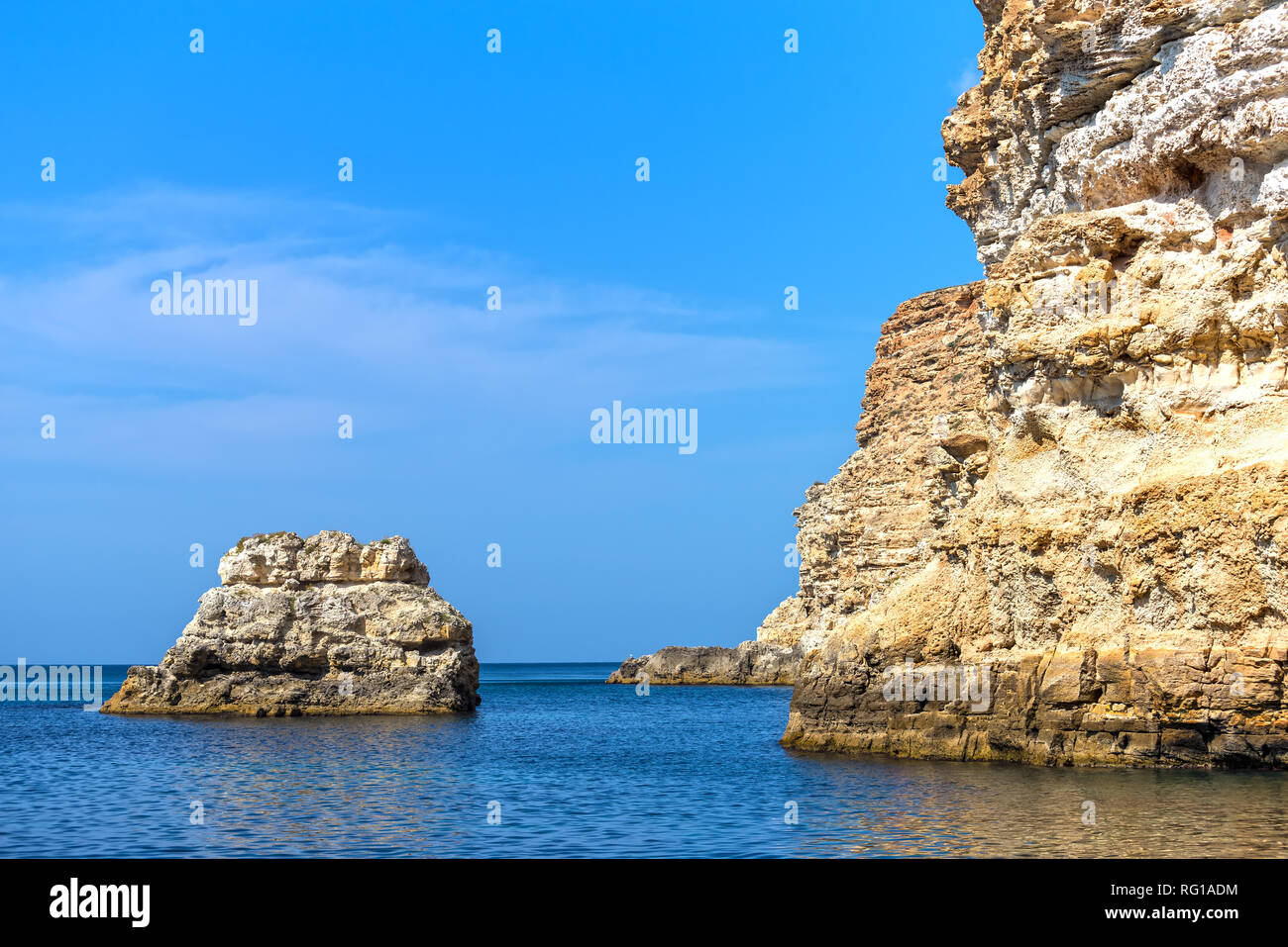 Rocky island in the sea near the rocky shore Stock Photo