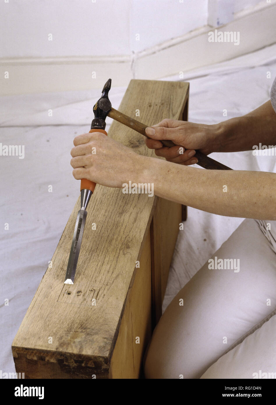 Hands using hammer and chisel on old drawer Stock Photo