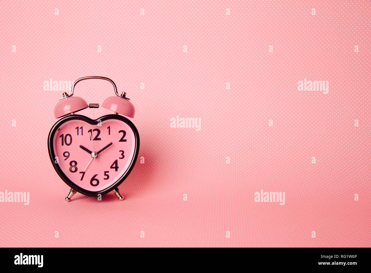 Heart shaped clock on pink background. Stock Photo