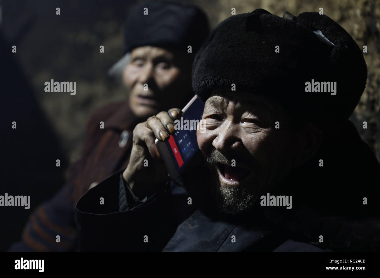 (190127) -- CHENGDU, Jan. 27, 2019 (Xinhua) -- Feng Wancai (R) talks with his daughter on the phone in Kuihua Village of Ganluo County, southwest China's Sichuan Province, Jan. 25, 2019. Feng Wancai, 91, moved to an isolated area in the remote Daliang Mountain in Sichuan after his wife Yang Wenying was diagnosed with leprosy in 1958, only one year after they got married. The place was recognized as a 'leprosy village', as leprosy patients gathered here to receive treatment. Years later, after most of the leprosy patients had been cured, the isolated land was renamed Kuihua Village, and geared  Stock Photo