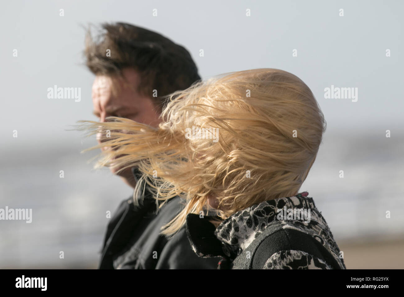 Blackpool, Lancashire. 27th Jan, 2019. UK Weather. Gale force winds at the coast. Visitors to the seaside town have to endure severe winds with pedestrians being blown over on the seafront promenade. Storm , blow, tempest, flyaway hair, tangled tresses, bad hair day on the seafront promenade. Credit:MediaWorldImages/AlamyLiveNews Stock Photo