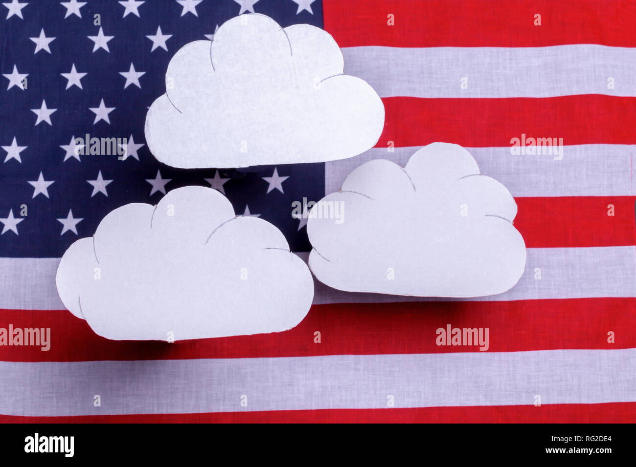 American flag star spangled banner with three white clouds floating over the flag. Red white and blue old glory country symbol with cutout toy weather Stock Photo
