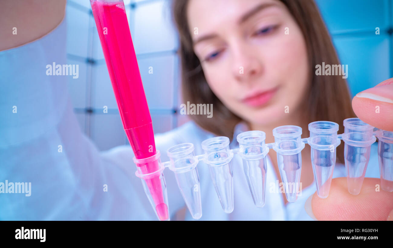 Young woman fill PCR microtubes with dispenser Stock Photo