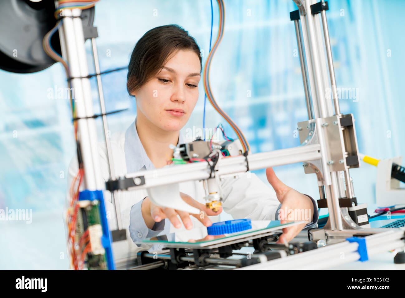 female student or laboratory assistant in the automation laboratory is debugging the work of the 3d printer. 3d printer is a device for modeling objec Stock Photo