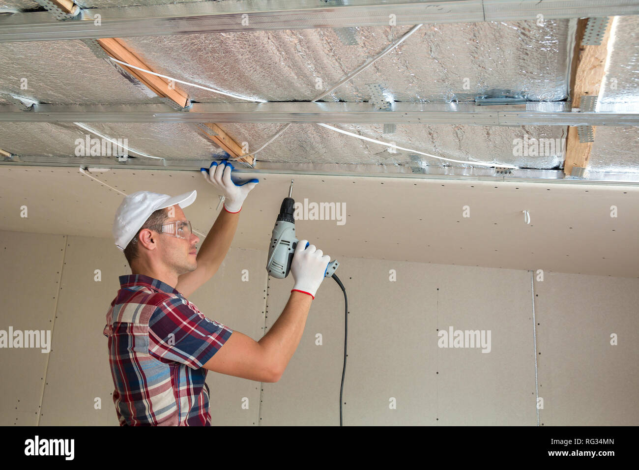 Young Man In Goggles Fixing Drywall Suspended Ceiling To Metal