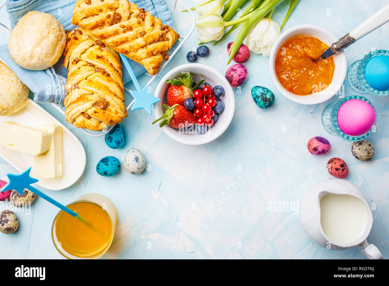 Easter Breakfast table. Colored eggs, buns, milk, juice and jam. Blue ...