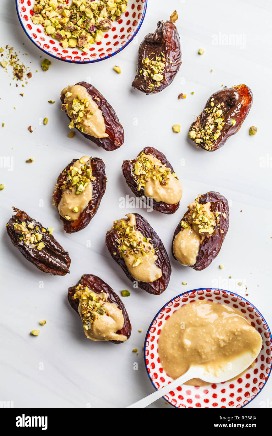Dates stuffed with peanut butter and pistachios on a white background
