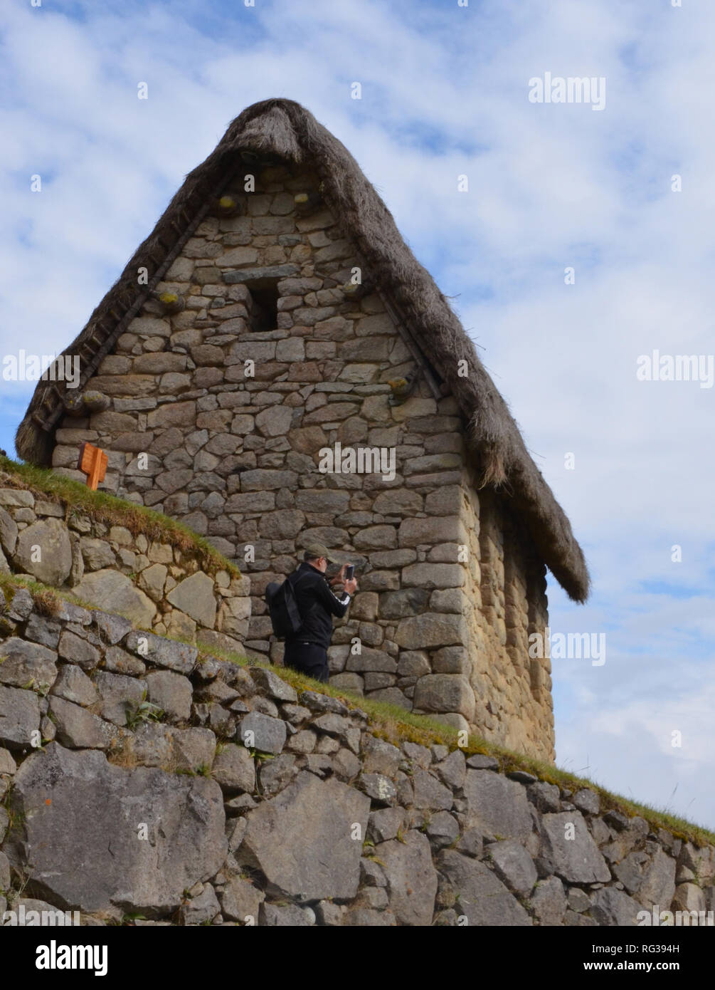 MACHU PICCHU / PERU, August 16, 2018: A tourist takes a photography from behind guardhouse in Machu Picchu ruins Stock Photo