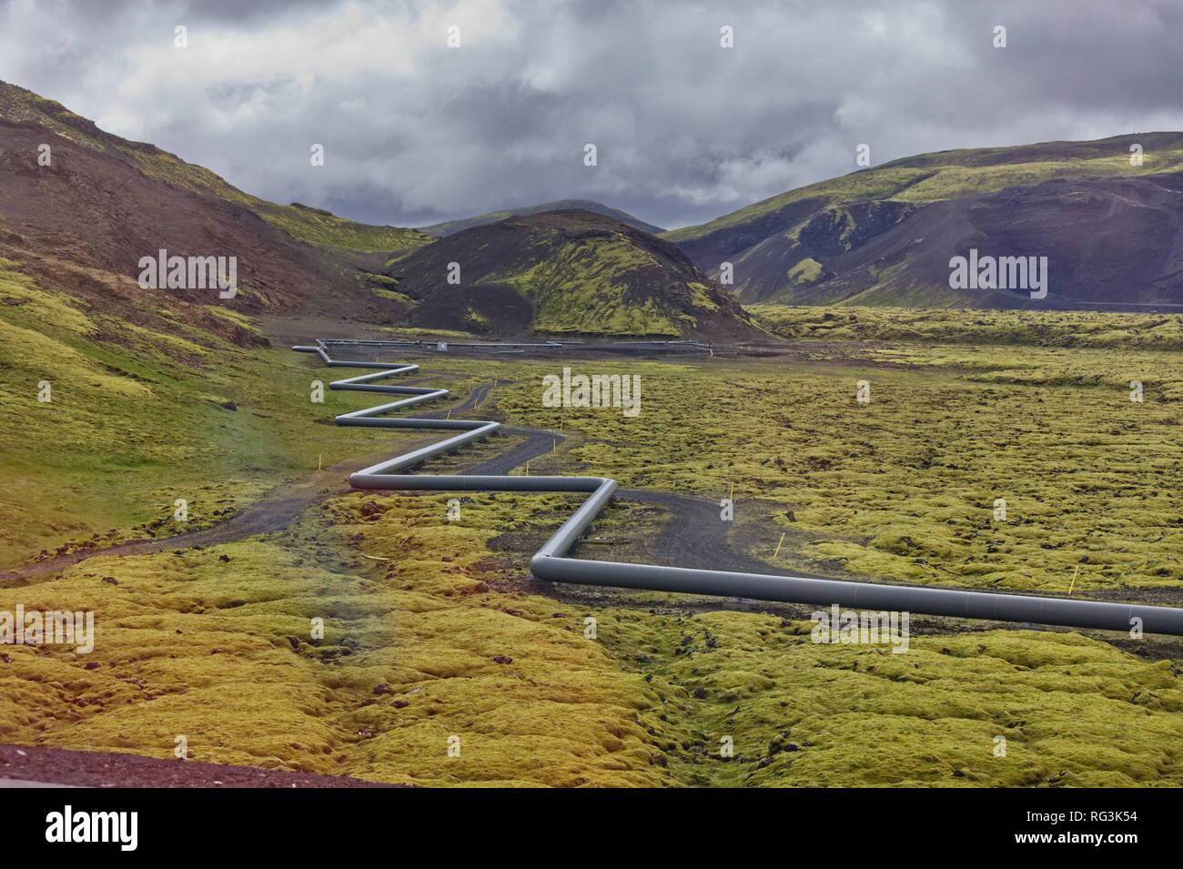 a metal pipeline winds its way through the rugged Icelandic terrain Stock Photo