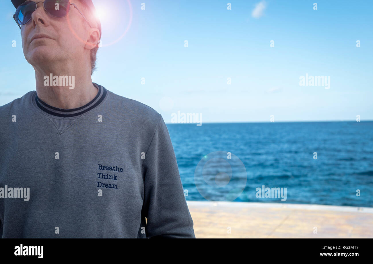 close up of a relaxed man wearing a sweat shirt with the slogan 'breathe, think, dream'. Stock Photo