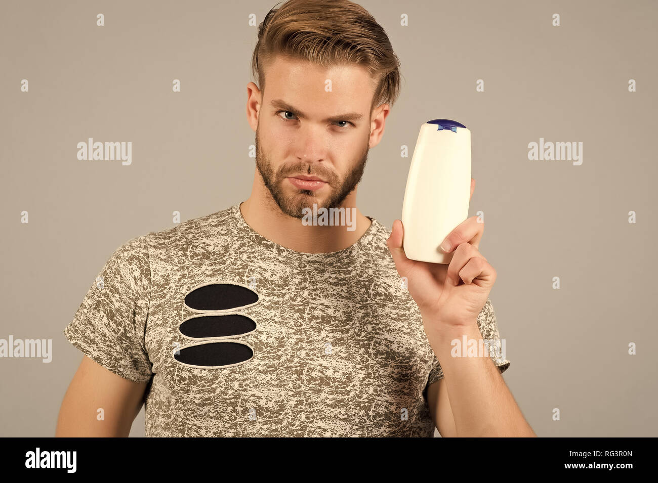 Man enjoy freshness after washing hair with shampoo. Guy with hairstyle  holds bottle shampoo, copy space. Hair care and beauty supplies concept. Man  strict face holds shampoo bottle, grey background Stock Photo -
