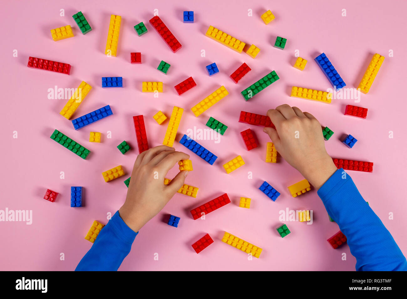 Kid hands playing with colorful building plastic bricks on pink ...