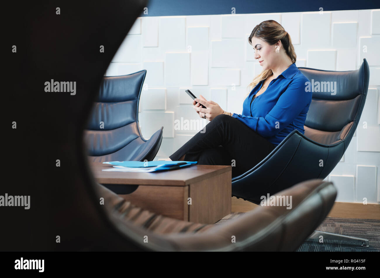 Serious Business Woman With Smartphone Sitting In Office Waiting Room Stock Photo
