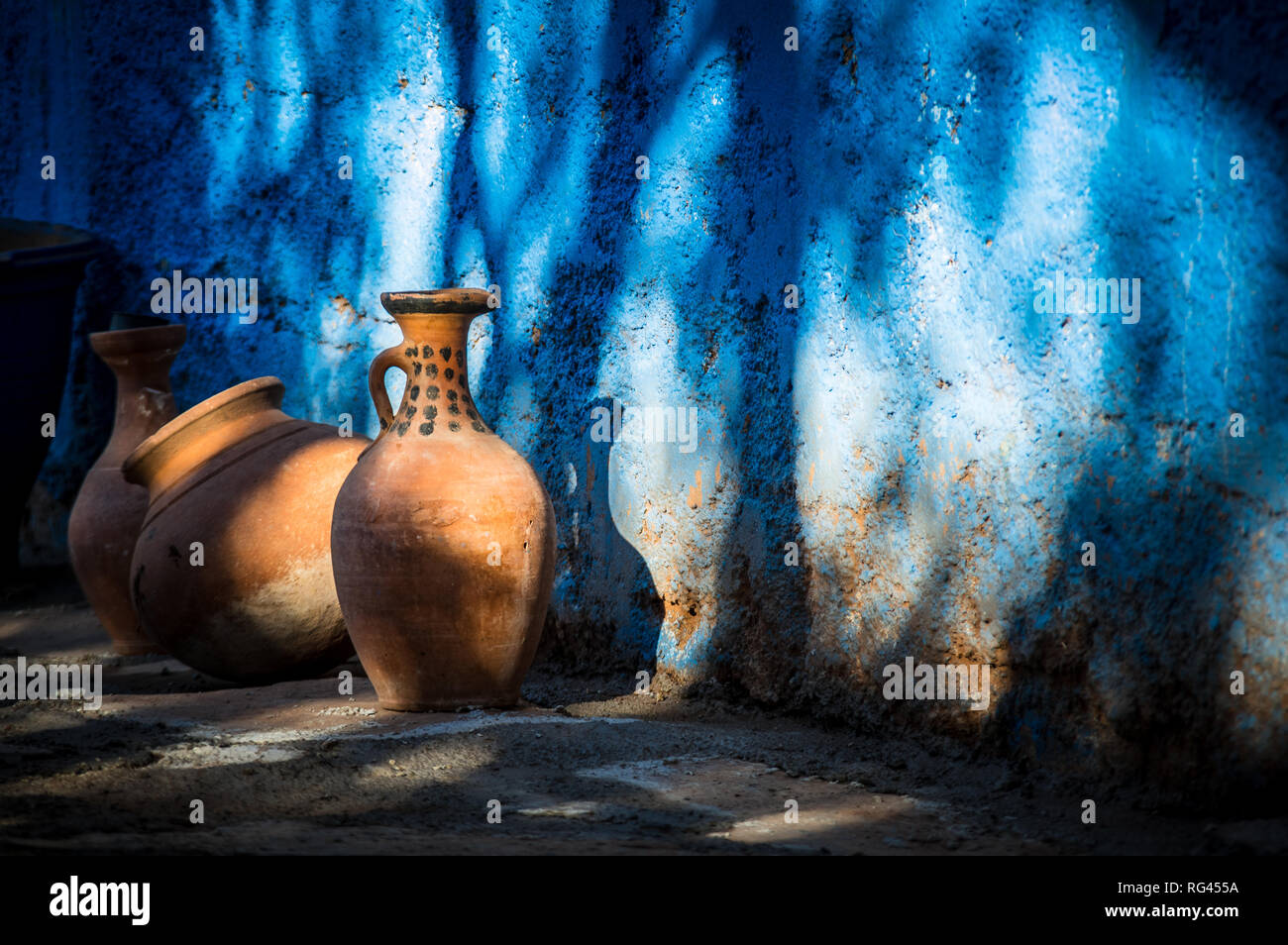 Pottery jars leaning against a blue wall Stock Photo