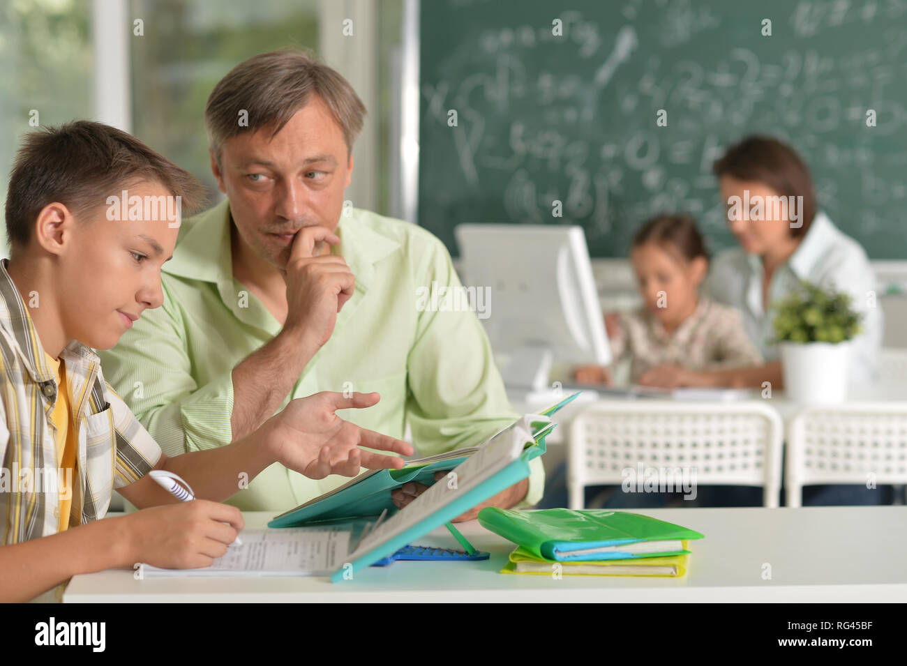 Father helping his son doing homework in classroom Stock Photo - Alamy