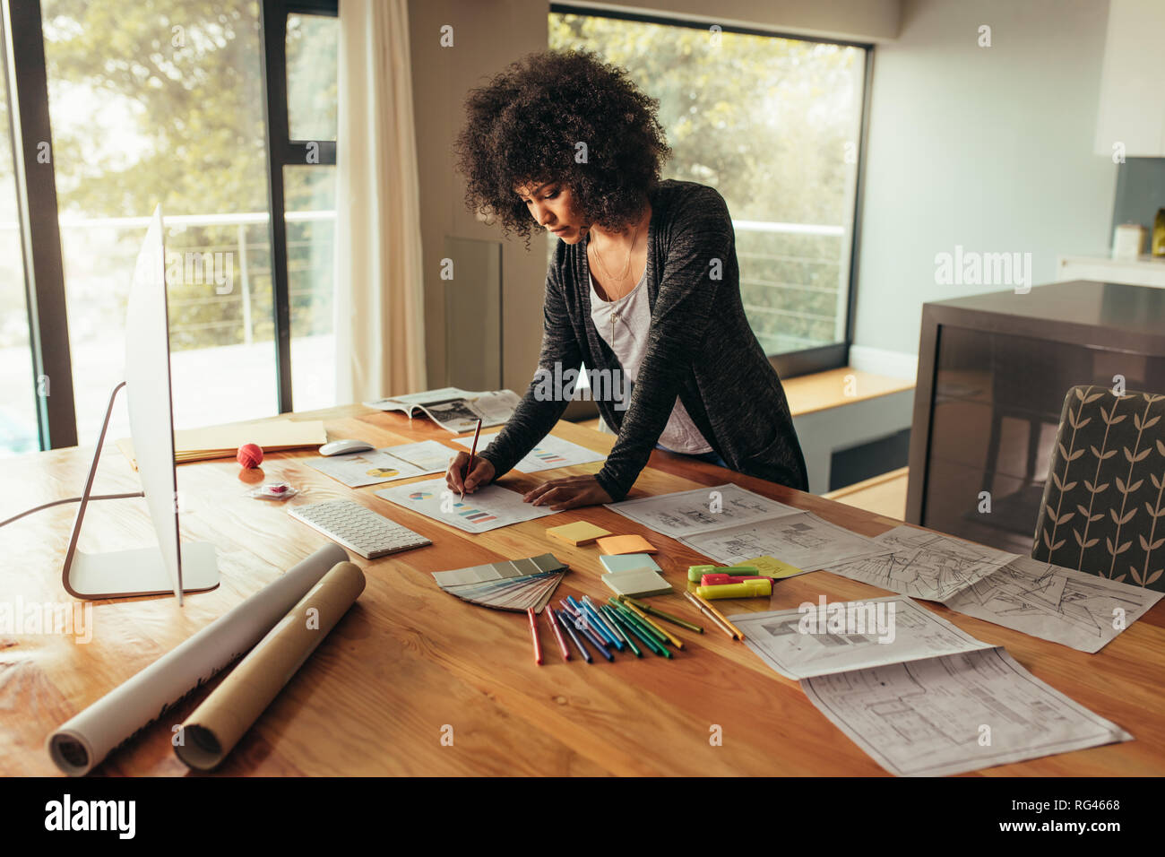 Young african businesswoman working on project. Woman working at home office, writing on a graph on a table. Stock Photo