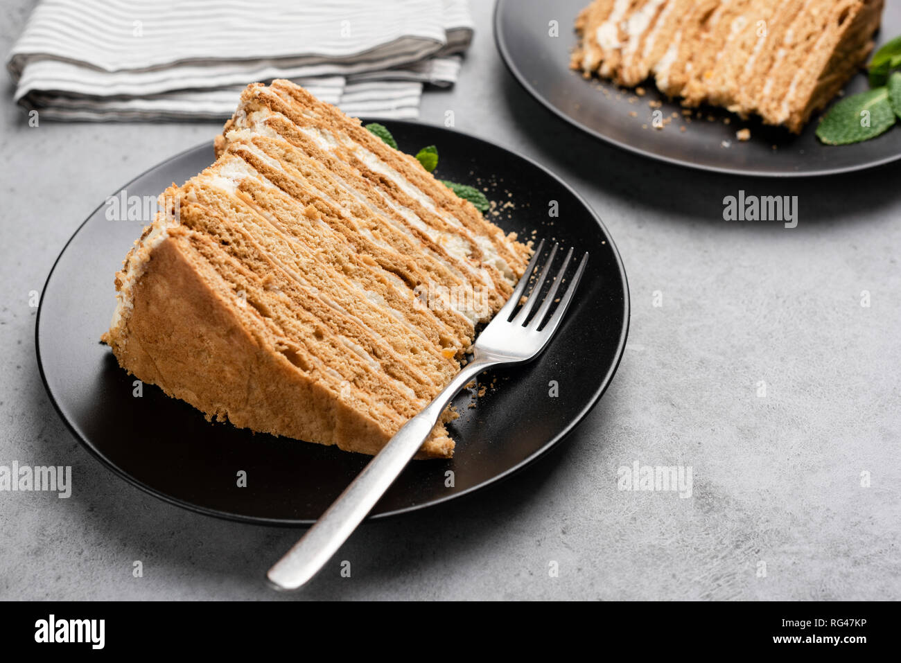 Layered honey cake on black plate. Russian Medovik cake with many biscuit layers and custard cream Stock Photo