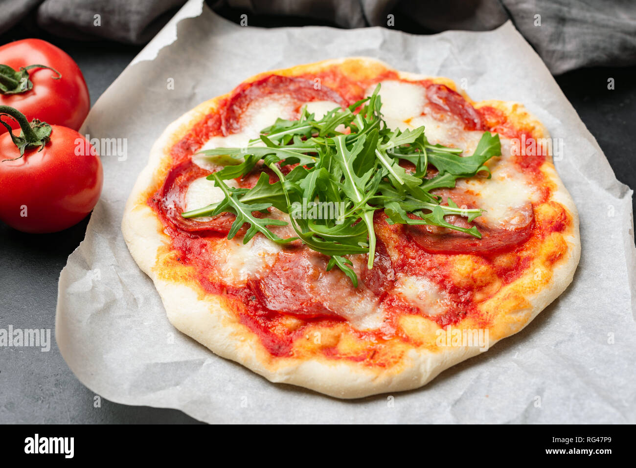 Tasty Pizza With Salami, Tomato Sauce, Cheese and Arugula. Selective focus Stock Photo