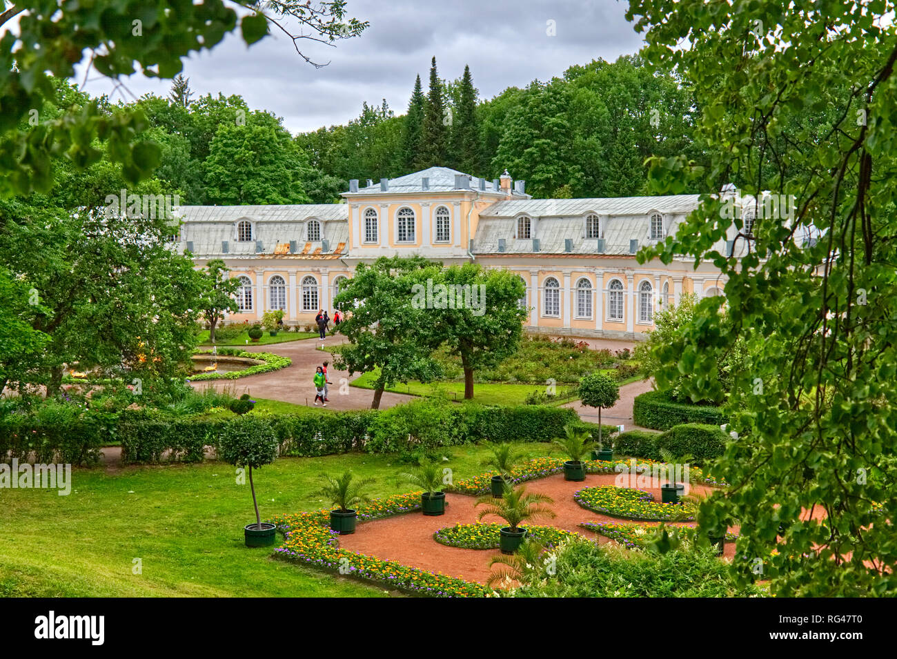 July 1, 2018: St. Petersburg, Russia: Looking through the summer green trees at the white and yellow building that houses a restaurant in Peterhof's g Stock Photo
