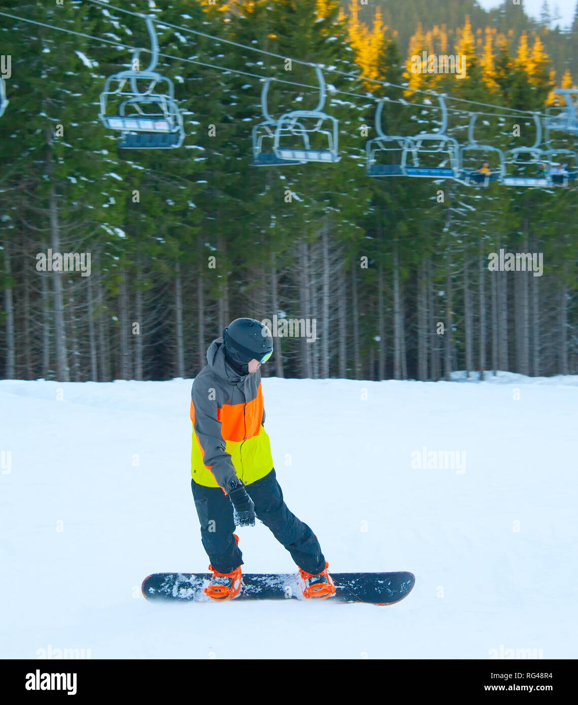 Boy riding snowboard ski lift and fir sunny forest in the background Boy riding snowboard ski lift and fir sunny forest in the background