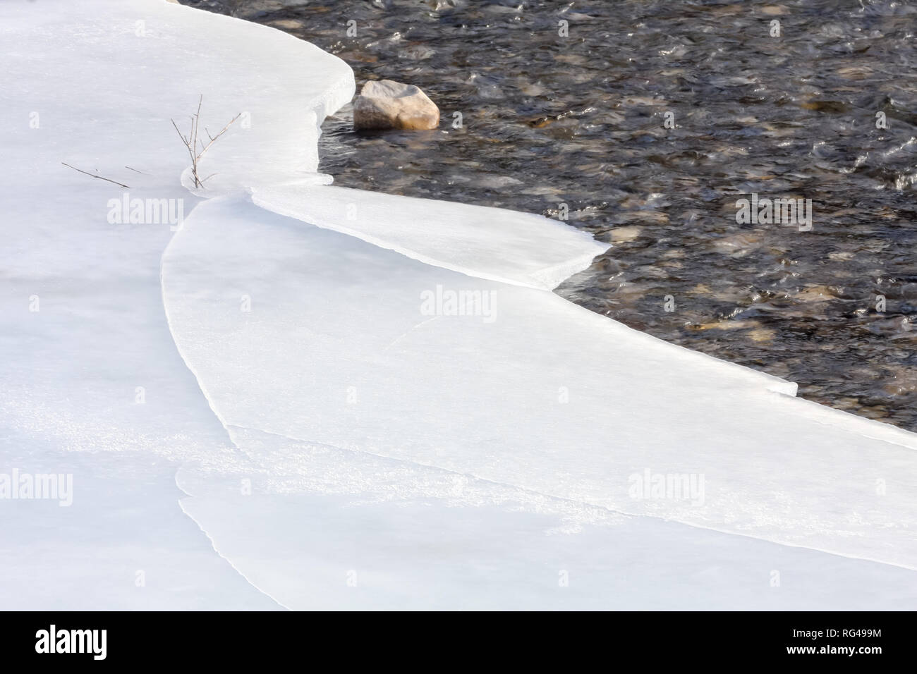 Cracks in ice in Elbow River in Kananaskis area near Bragg Creek, Alberta, Canada, on warm winter day (12 C) thanks to a chinook. Stock Photo