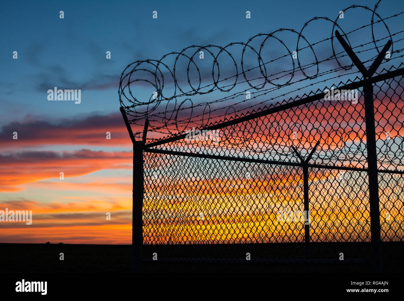 Dramatic sunset with chain link fence and razor wire silhouette Stock ...