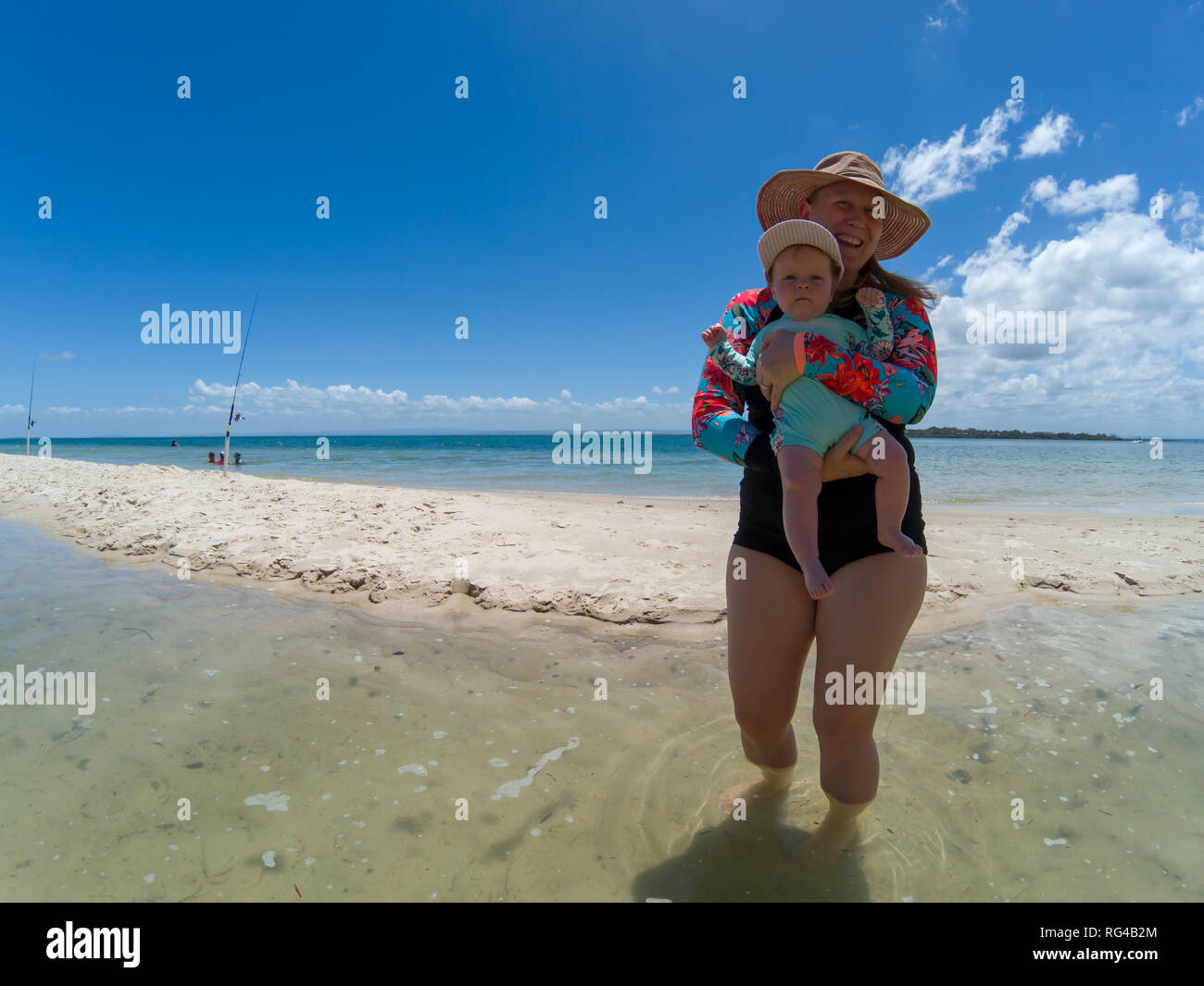 A blonde mum in her late thirties with baby playing at beach. Stock Photo