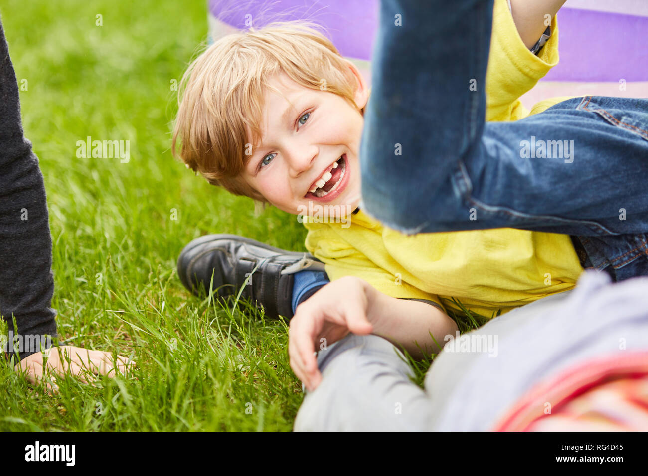 Boy laughs cheekily at a brawl with friends in the park on vacation in the summer Stock Photo