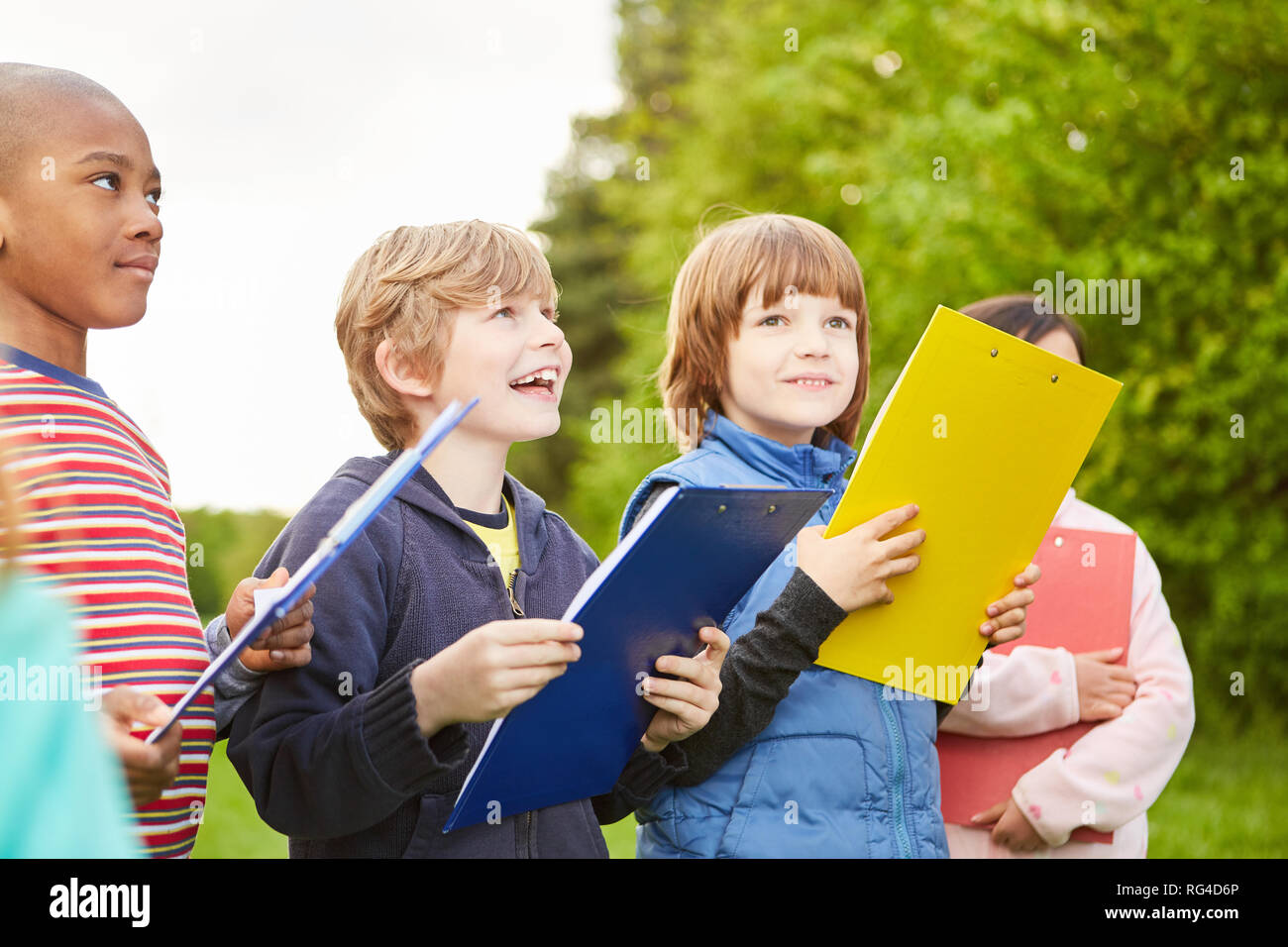 Group of kids together play scavenger hunt at kids birthday with clipboard Stock Photo