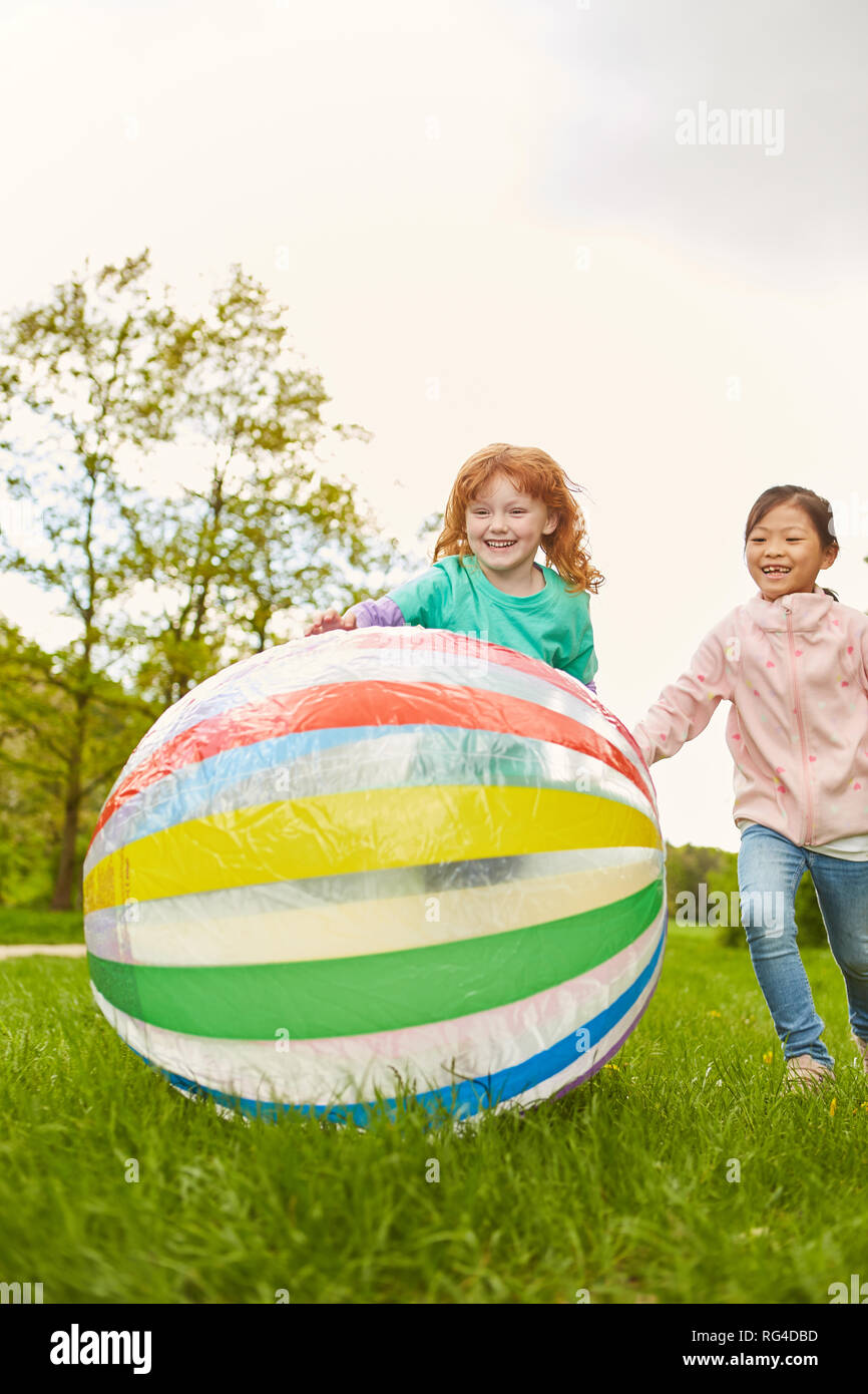 Two girls have fun playing ball together in the park in summer vacations Stock Photo
