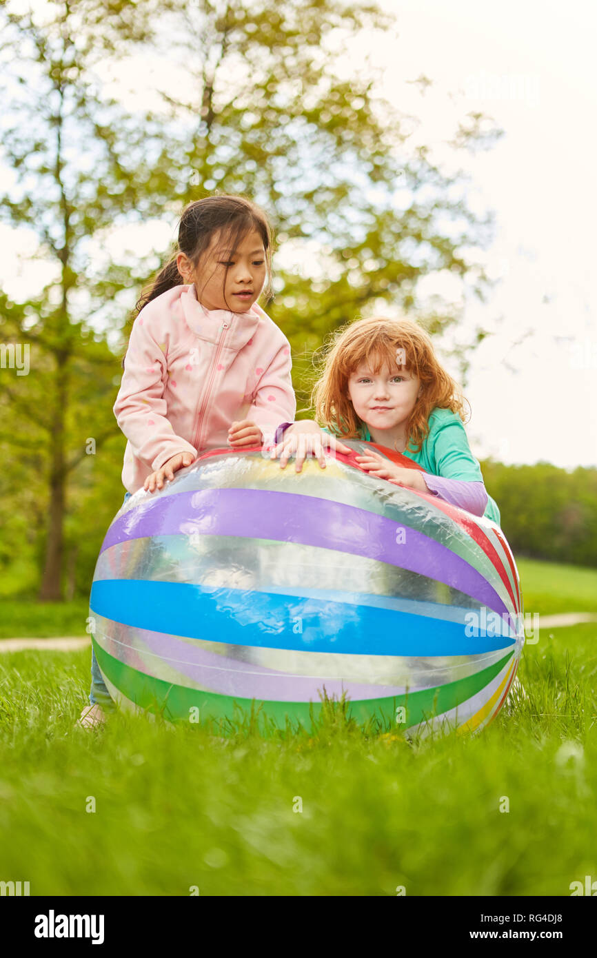 Two girls as girlfriends play together with a ball in the park in summer Stock Photo