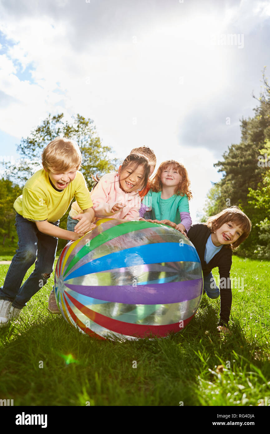 Group of kids plays hilariously with a colorful ball in the park in ...
